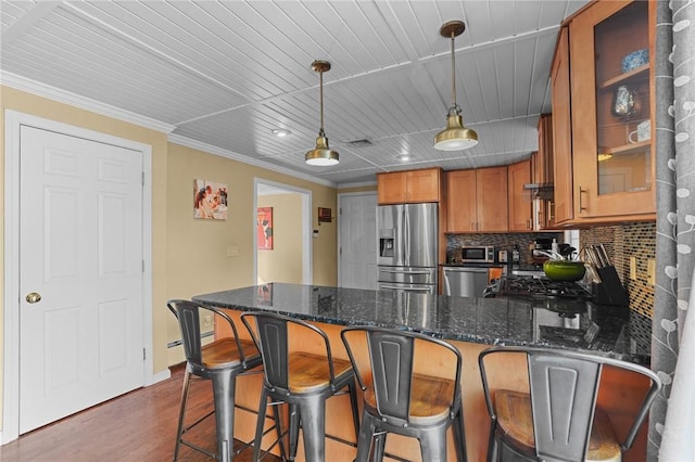 kitchen featuring decorative light fixtures, stainless steel appliances, decorative backsplash, ornamental molding, and dark stone countertops