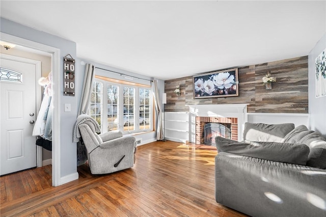 living room featuring a brick fireplace, wooden walls, and hardwood / wood-style flooring