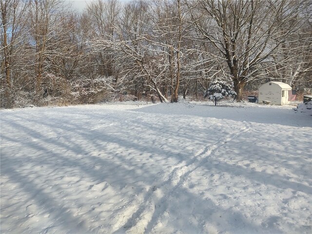 yard layered in snow featuring a storage shed