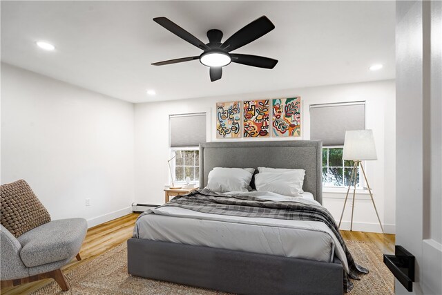 bedroom with ceiling fan, light hardwood / wood-style flooring, and a baseboard radiator