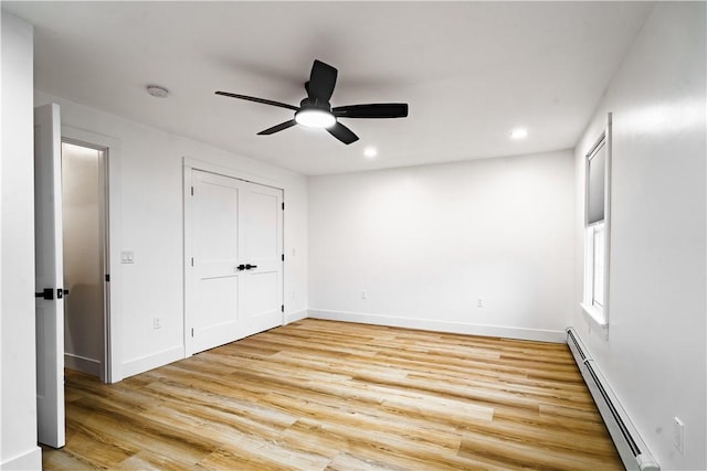 unfurnished bedroom with baseboard heating, a closet, light hardwood / wood-style floors, and ceiling fan