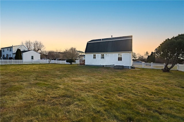 back house at dusk featuring a yard