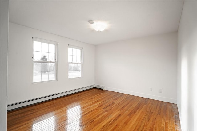 spare room featuring wood-type flooring and a baseboard radiator