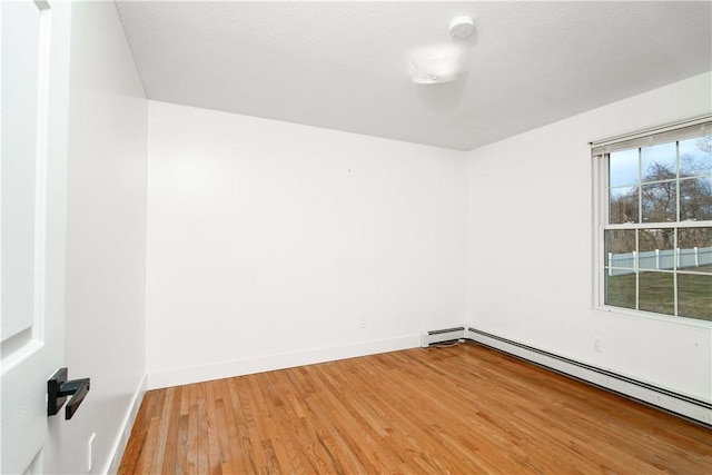 spare room with baseboard heating and wood-type flooring