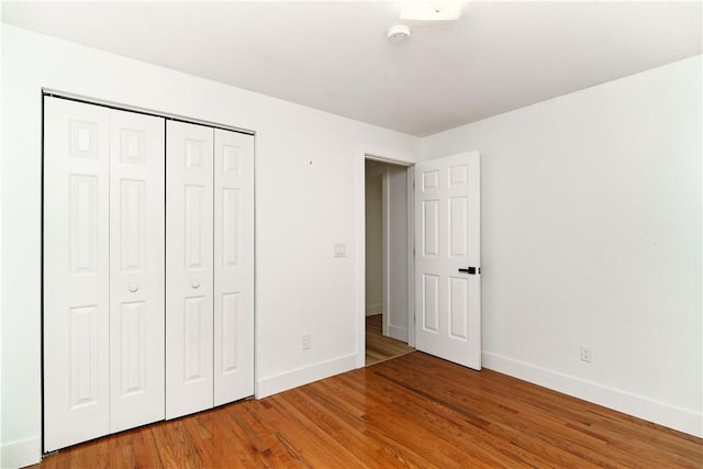 unfurnished bedroom with hardwood / wood-style flooring and a closet