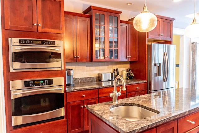 kitchen featuring sink, stainless steel appliances, light stone countertops, and pendant lighting