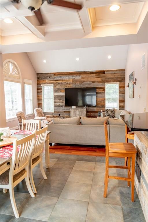 dining room featuring a fireplace, ceiling fan, and wooden walls