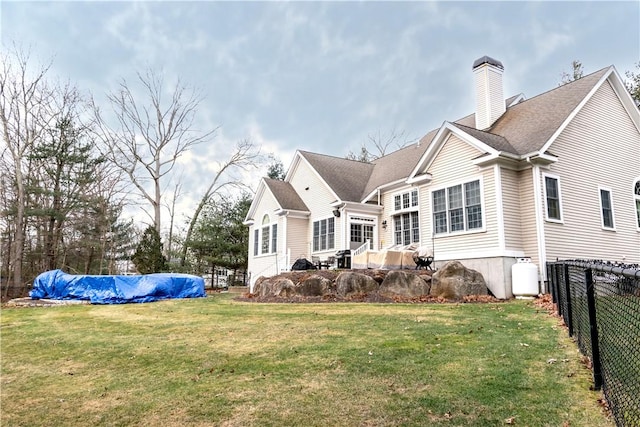 back of property with a yard and a covered pool