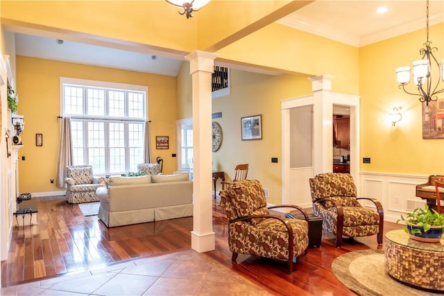 tiled living room featuring crown molding, an inviting chandelier, and decorative columns