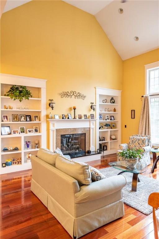 living room with hardwood / wood-style flooring, vaulted ceiling, and built in features