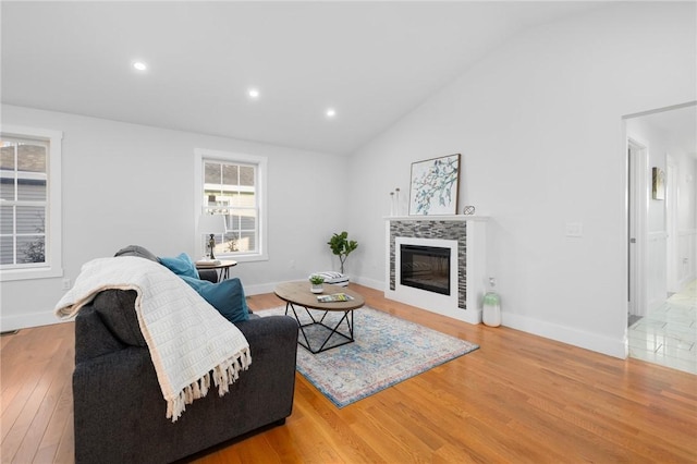 living room featuring vaulted ceiling, hardwood / wood-style floors, and a tiled fireplace