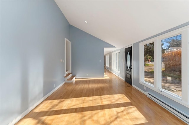 empty room with light hardwood / wood-style floors, baseboard heating, and lofted ceiling