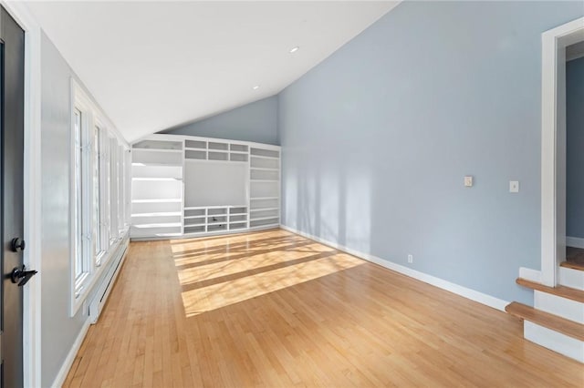 spare room featuring a baseboard heating unit, vaulted ceiling, and light hardwood / wood-style flooring