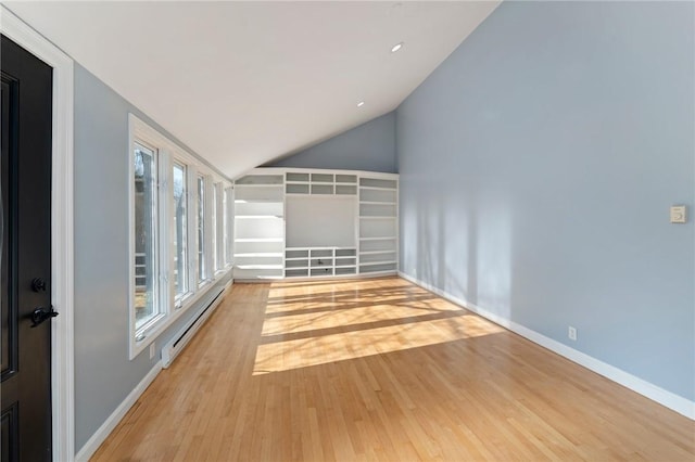 empty room with lofted ceiling, a baseboard radiator, and light hardwood / wood-style flooring