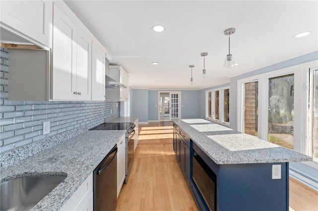 kitchen with white cabinets, a center island, decorative light fixtures, and black dishwasher