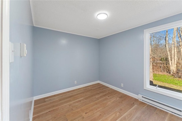 empty room featuring light hardwood / wood-style floors, a textured ceiling, and a baseboard heating unit