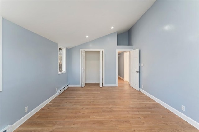 unfurnished bedroom featuring light wood-type flooring, lofted ceiling, and a baseboard heating unit