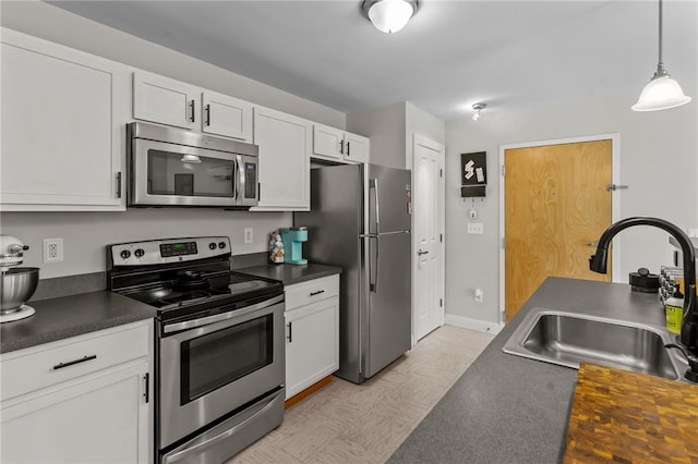 kitchen with decorative light fixtures, white cabinets, appliances with stainless steel finishes, and sink