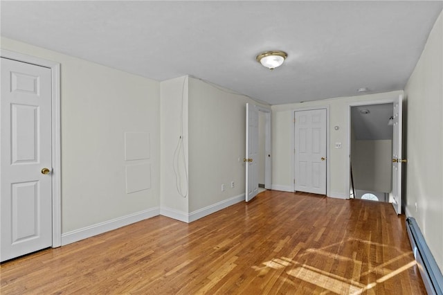 unfurnished bedroom featuring baseboard heating and hardwood / wood-style floors