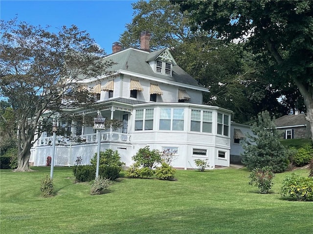 back of property featuring a chimney and a yard