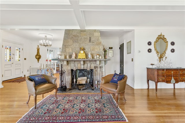 living area featuring a chandelier, a stone fireplace, wood finished floors, beam ceiling, and crown molding