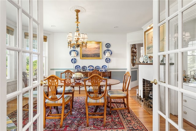 dining area featuring light wood-style flooring, ornamental molding, a chandelier, and french doors