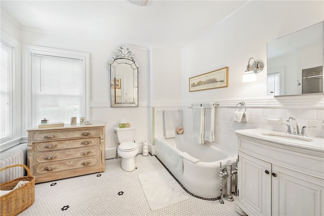 bathroom with a wainscoted wall, a garden tub, radiator, toilet, and vanity