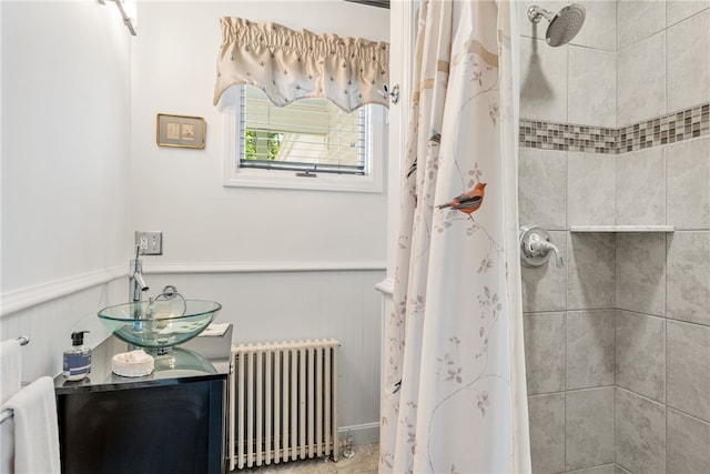 bathroom featuring radiator, wainscoting, a tile shower, and vanity