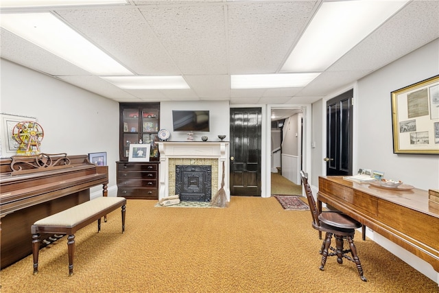 living area featuring a fireplace with flush hearth, a paneled ceiling, and carpet flooring