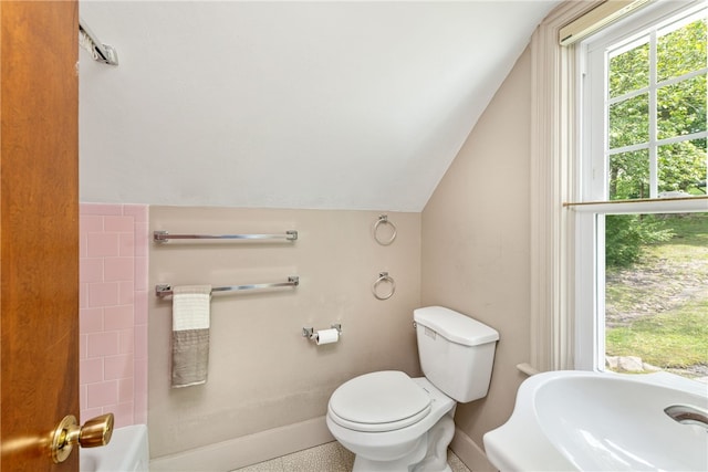 full bath with vaulted ceiling, a bathtub, toilet, and baseboards