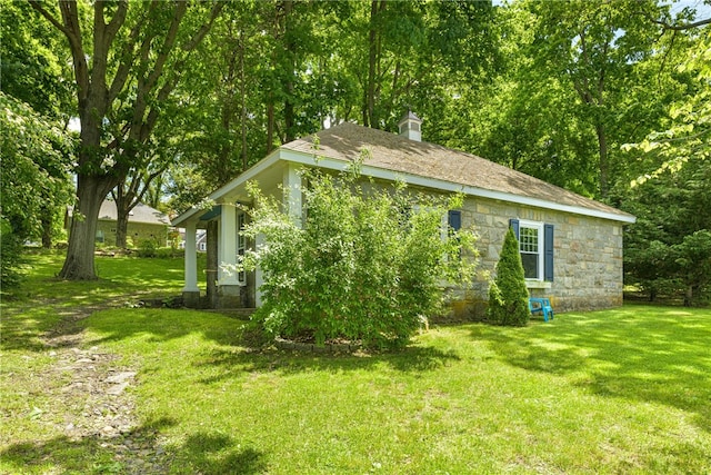 view of property exterior with stone siding, a lawn, and a chimney