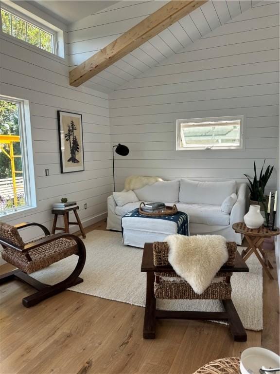 living room featuring hardwood / wood-style floors, wooden walls, and lofted ceiling with beams