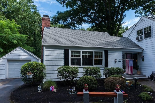 view of front facade with a garage, cooling unit, and an outbuilding