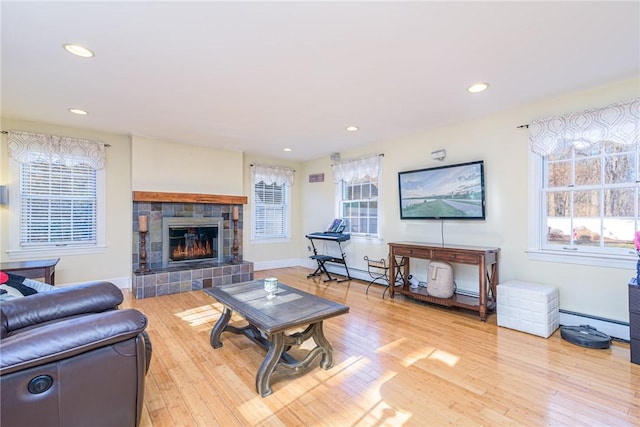 living room featuring a fireplace, a baseboard radiator, and wood-type flooring