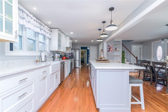 kitchen featuring appliances with stainless steel finishes, a center island, pendant lighting, white cabinets, and sink