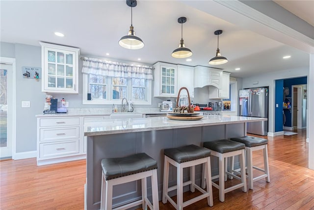 kitchen with a center island, stainless steel refrigerator, white cabinetry, and hanging light fixtures