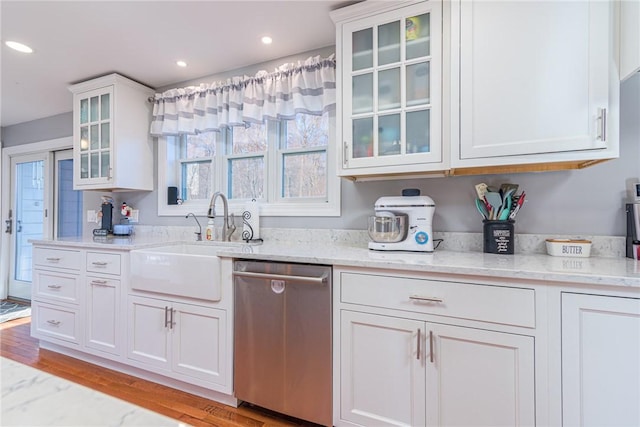 kitchen with light stone counters, stainless steel dishwasher, light hardwood / wood-style flooring, white cabinets, and sink