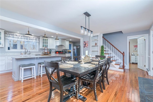 dining space featuring baseboard heating, light hardwood / wood-style flooring, and sink