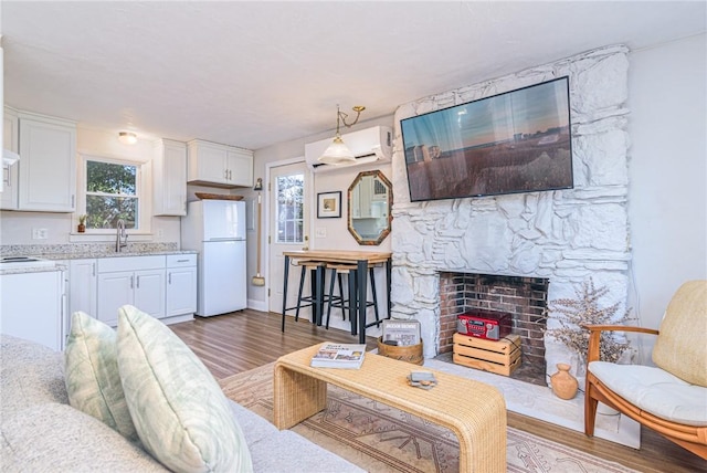 living room featuring dark wood-type flooring, a wall mounted AC, a wealth of natural light, and sink