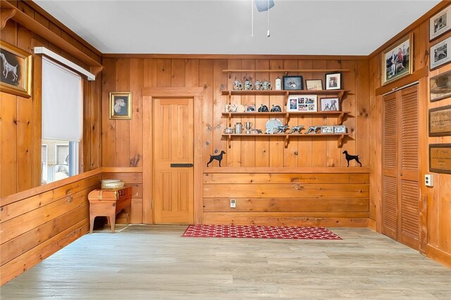 interior space with light hardwood / wood-style flooring and wooden walls