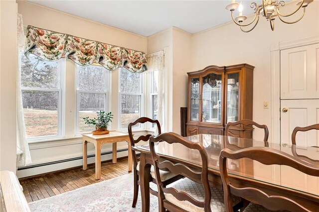 dining room featuring a baseboard heating unit, an inviting chandelier, hardwood / wood-style flooring, and plenty of natural light