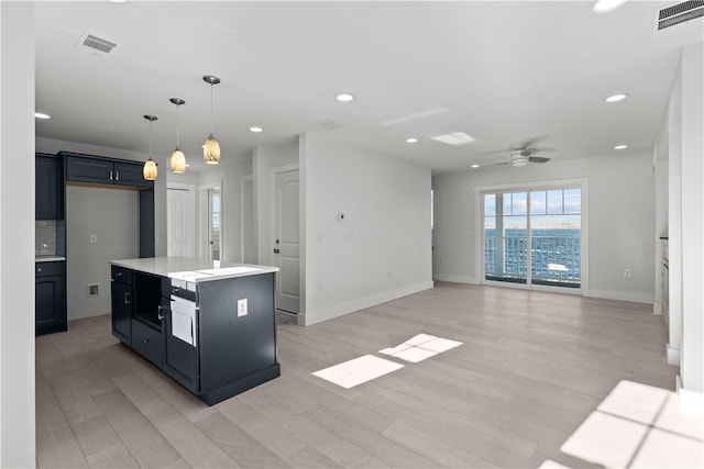 kitchen featuring pendant lighting, a kitchen island, decorative backsplash, ceiling fan, and light hardwood / wood-style flooring