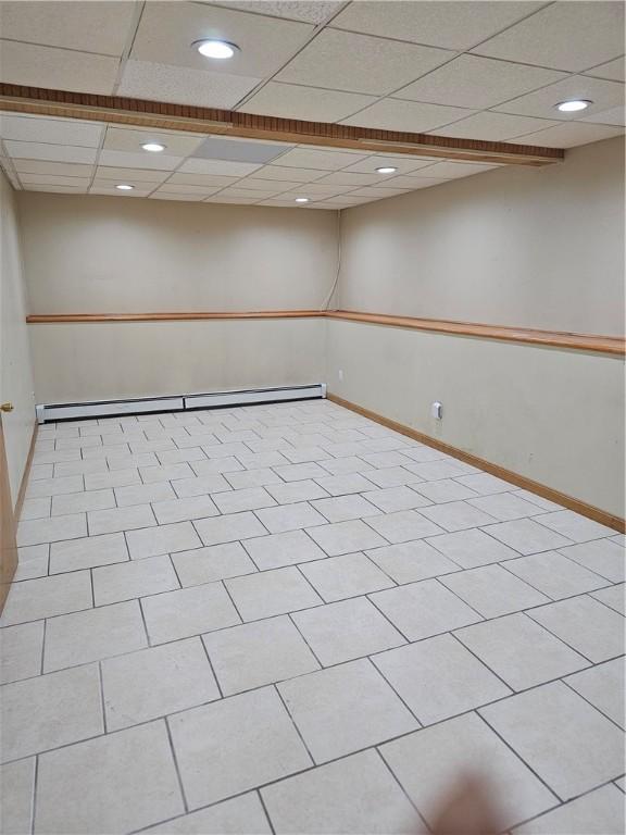 tiled spare room with baseboard heating and a paneled ceiling