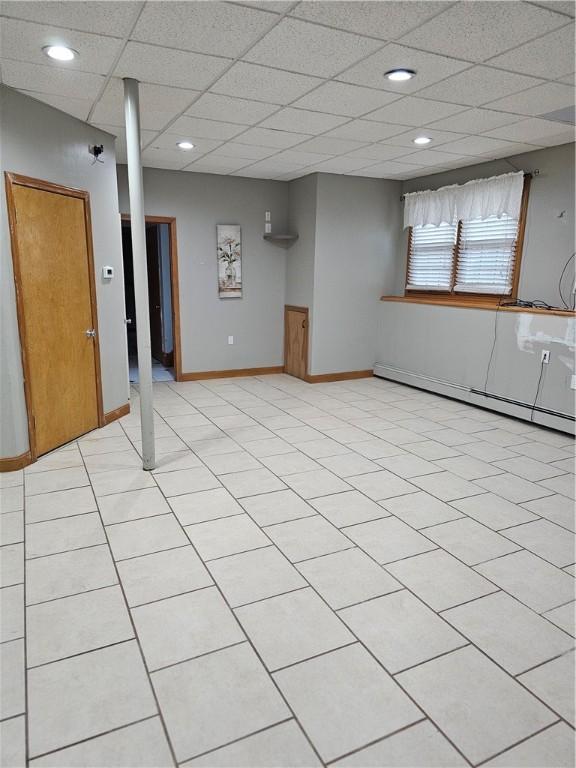 basement with a paneled ceiling and a baseboard radiator