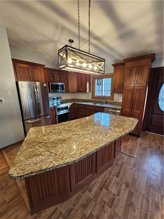 kitchen with appliances with stainless steel finishes, a kitchen breakfast bar, decorative light fixtures, and vaulted ceiling