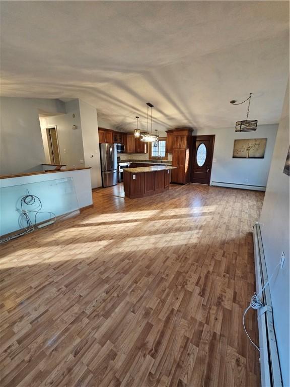 kitchen with hardwood / wood-style flooring, hanging light fixtures, stainless steel appliances, a kitchen island, and a baseboard heating unit