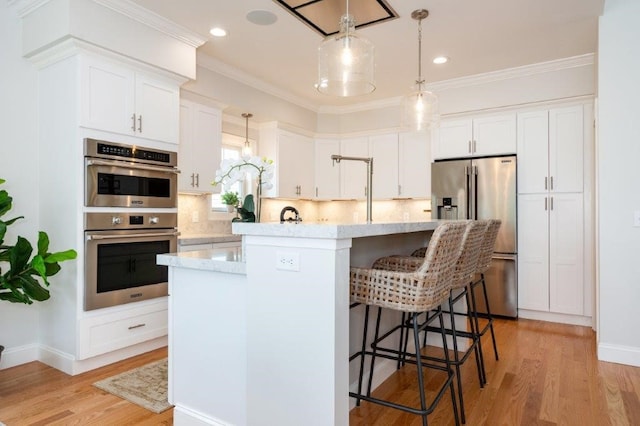 kitchen with a center island, light hardwood / wood-style floors, backsplash, white cabinetry, and appliances with stainless steel finishes