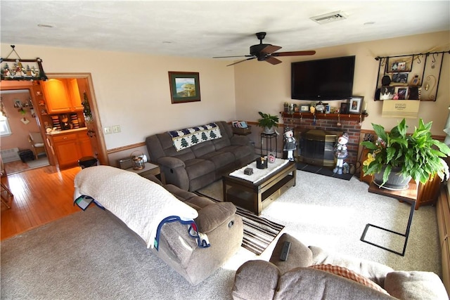 living room with a brick fireplace, ceiling fan, and hardwood / wood-style floors