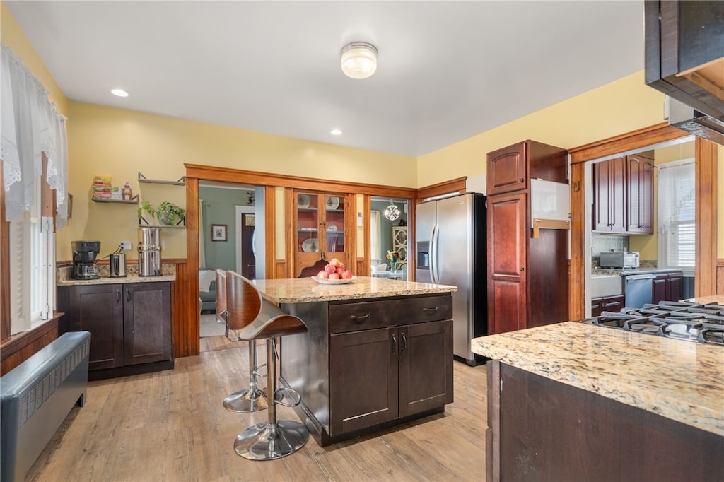 kitchen featuring radiator, stainless steel fridge, a breakfast bar area, a center island, and light wood-type flooring