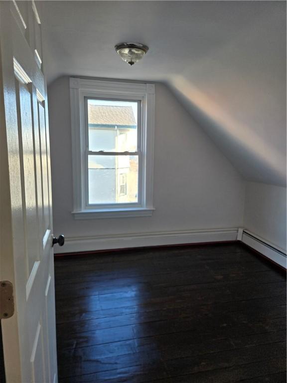 additional living space with lofted ceiling, dark hardwood / wood-style flooring, and baseboard heating